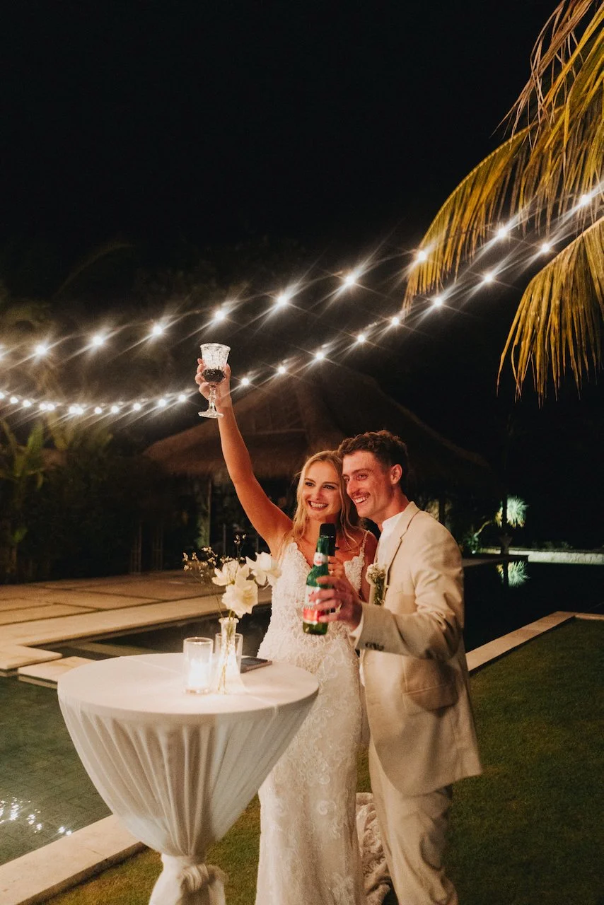 Bride and groom raising their glasses on the outdoor dance floor under fairy lights