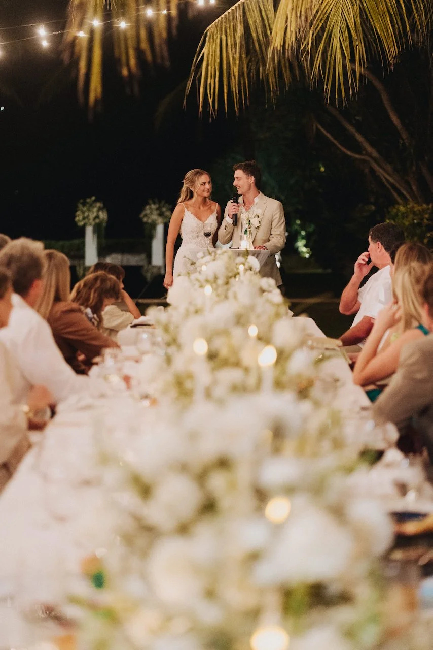 Groom Devin delivering his wedding speech at a candlelit reception table in Tabanan