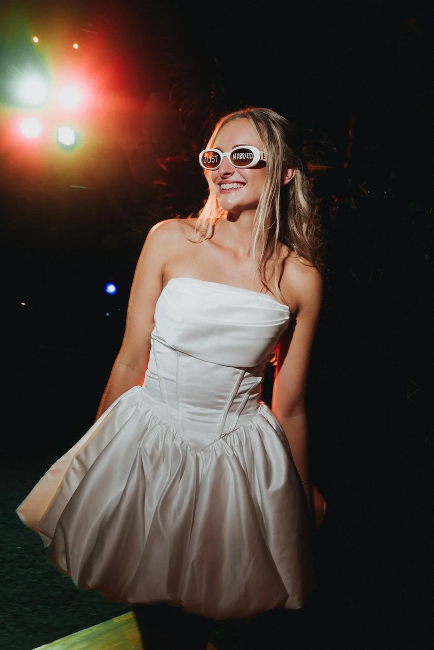 Bride wearing a short white party dress and sunglasses on the dance floor at night