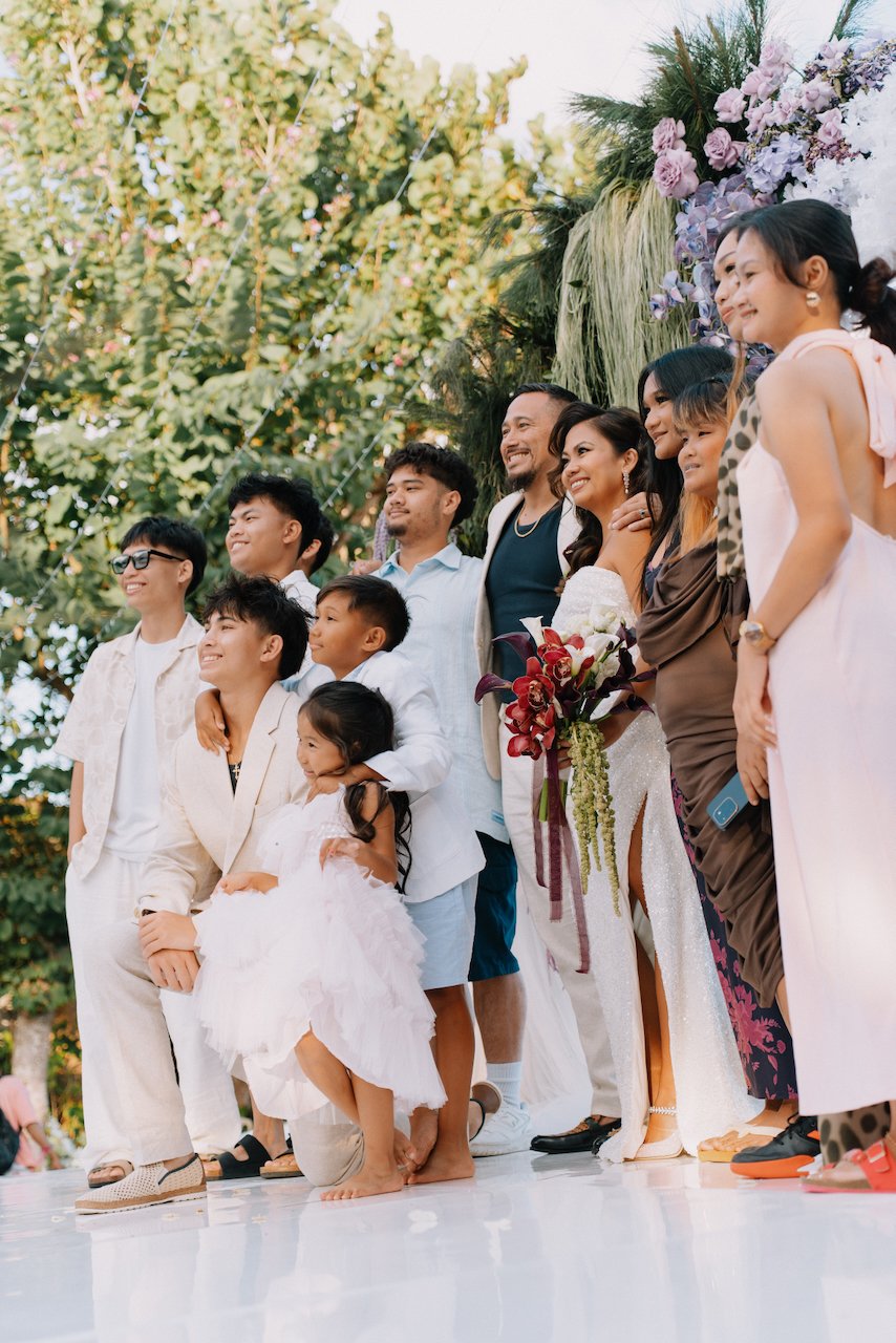 Family group photo on a clear stage during a Bali vow renewal celebration
