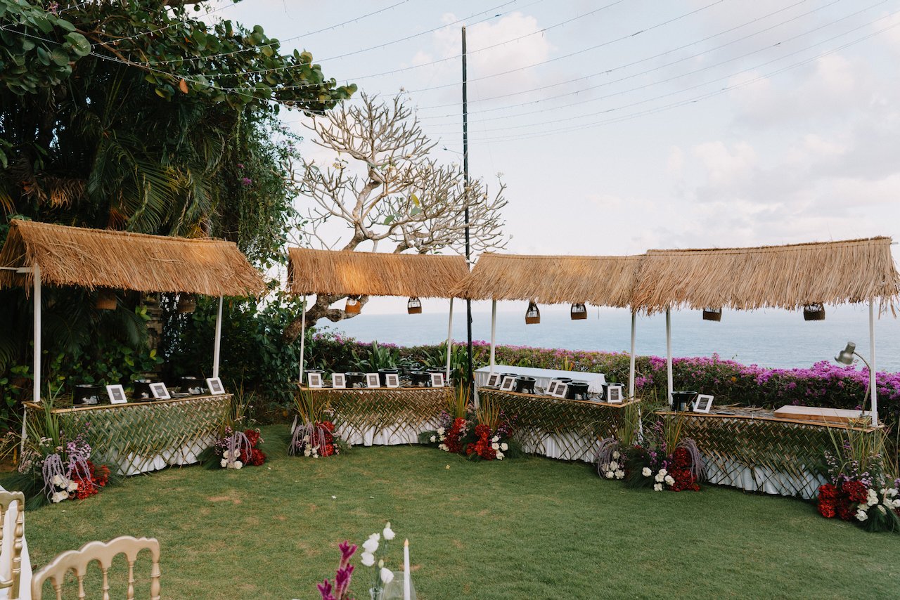 Thatch roof food stalls set up on a grassy lawn overlooking the ocean in Bali