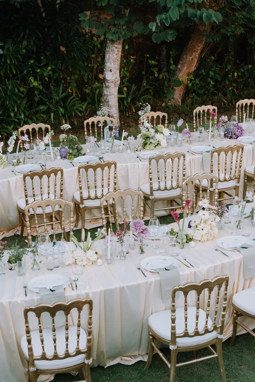 Long banquet tables arranged on a villa lawn under warm string lights