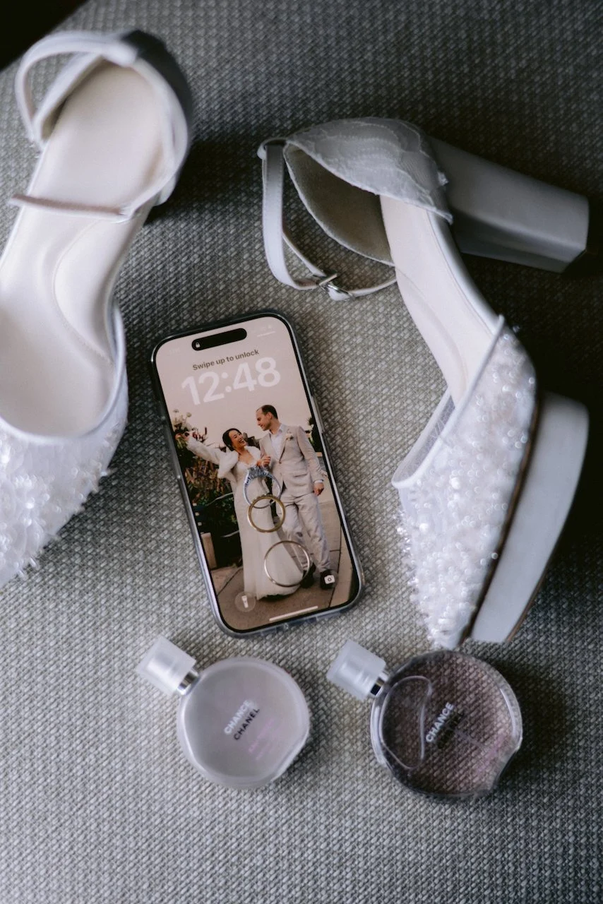 White bridal heels with a smartphone and perfume bottles prepared for a Bali wedding