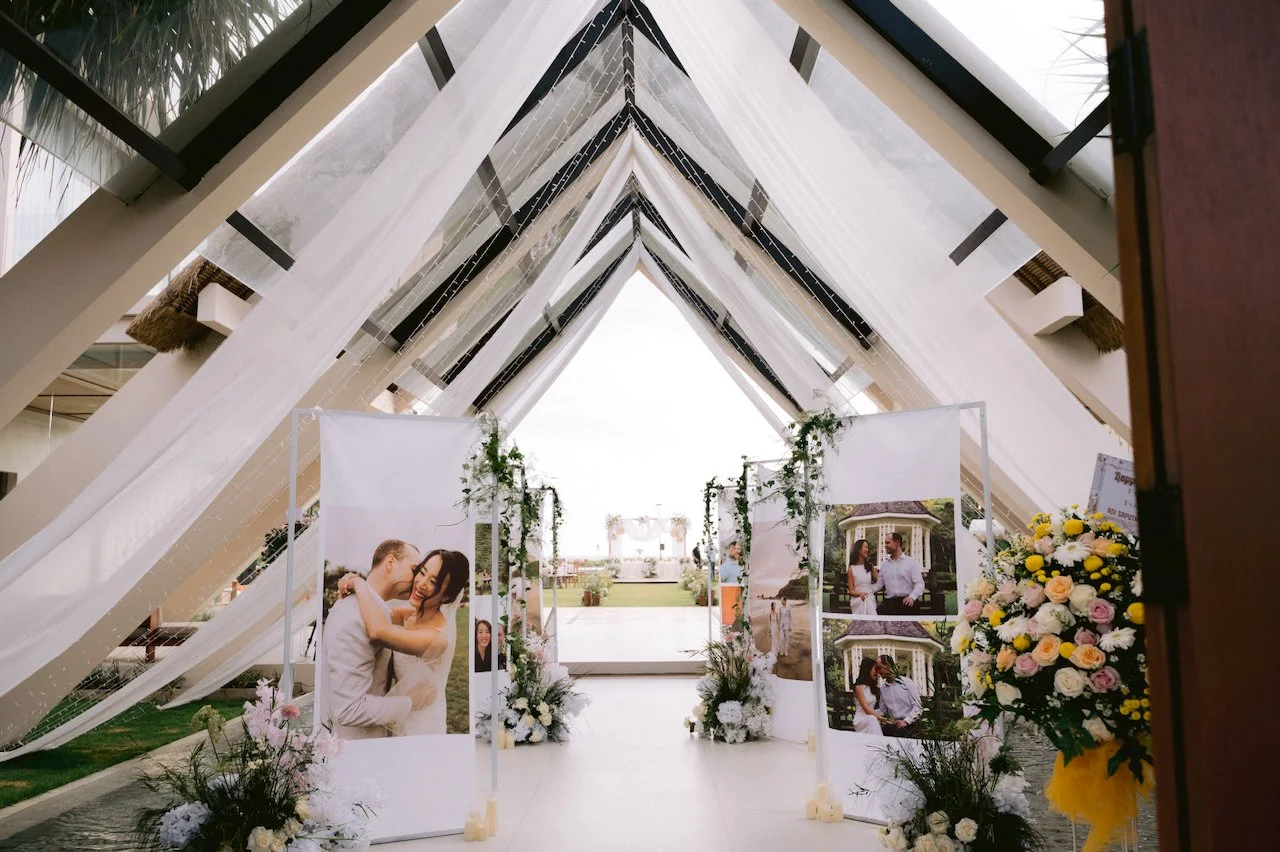 A frame chapel entrance decorated with white draping and floral arrangements in Bali