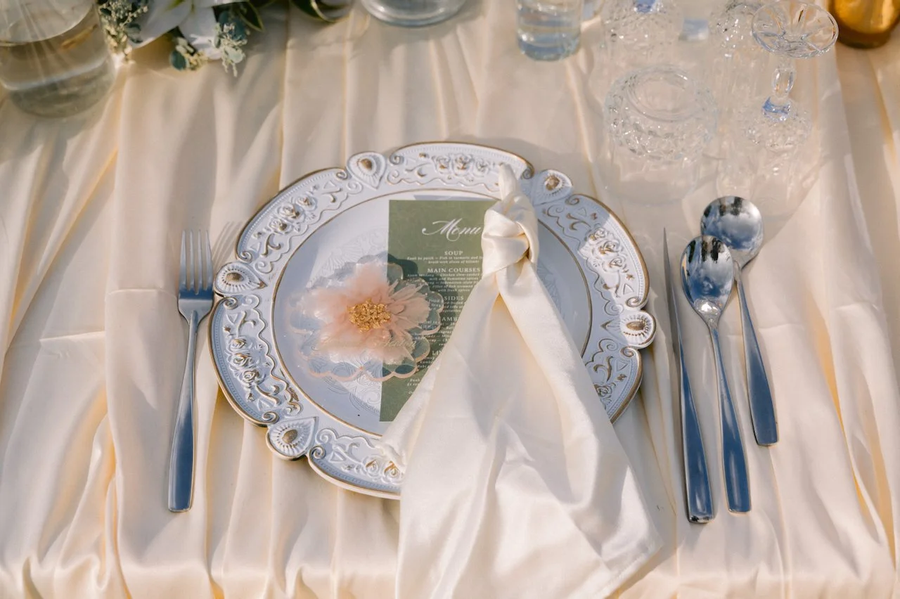 Elegant wedding table setting with a floral plate and folded white napkin