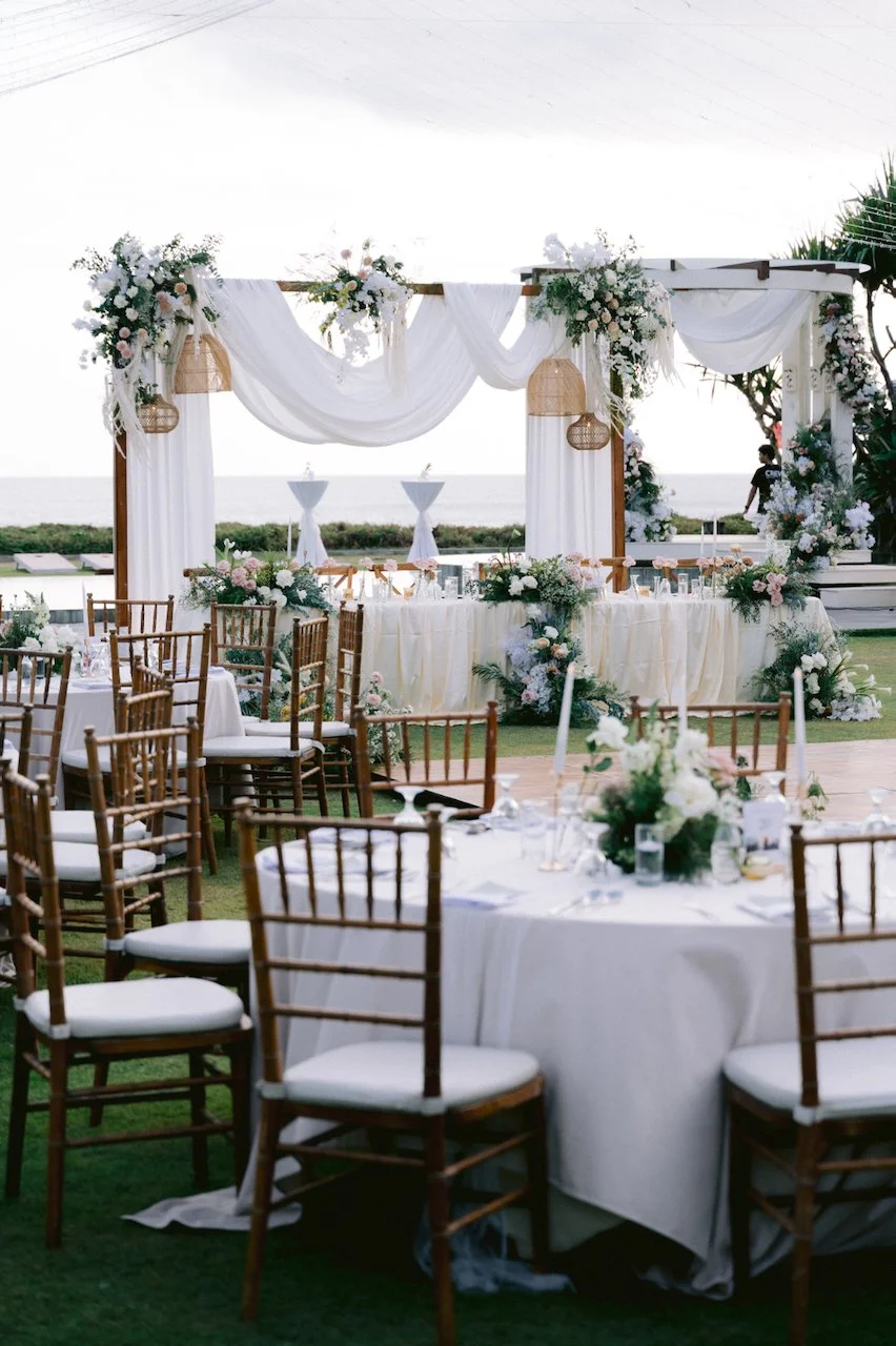 Outdoor wedding reception tables set on a lawn with a white draped canopy