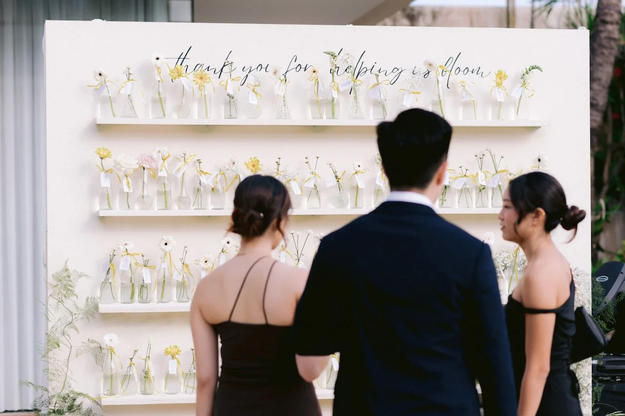 Guests finding their seats at a flower vase escort card display