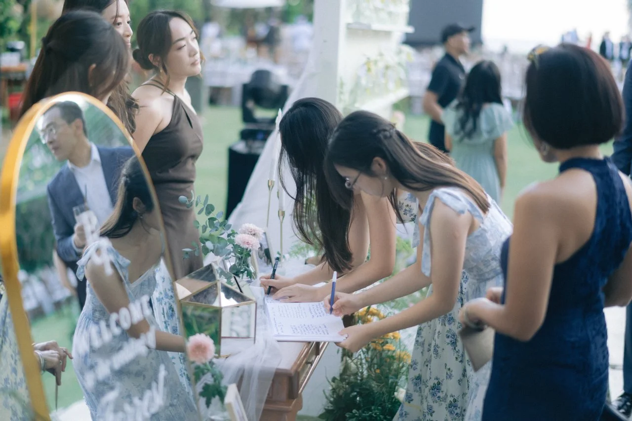 Wedding guests signing a guestbook on a mirror welcome sign before the ceremony
