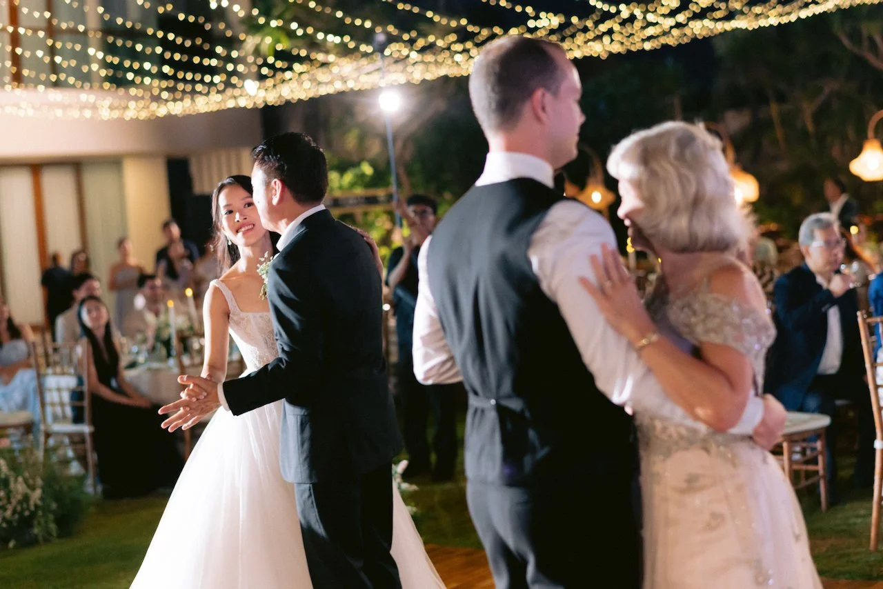 Wedding guests enjoying a dance together on an outdoor wooden floor under string lights