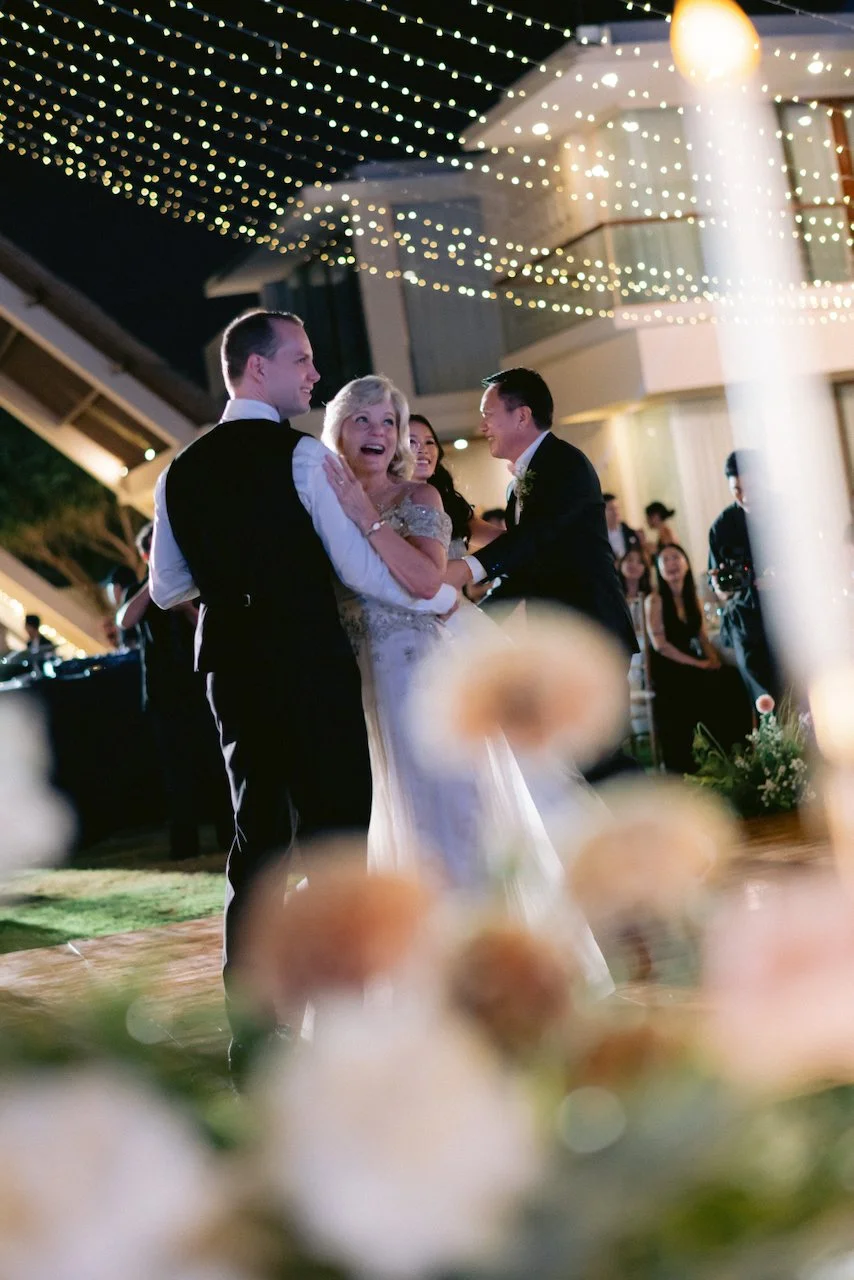 Bride and groom sharing their first dance outdoors surrounded by wedding guests