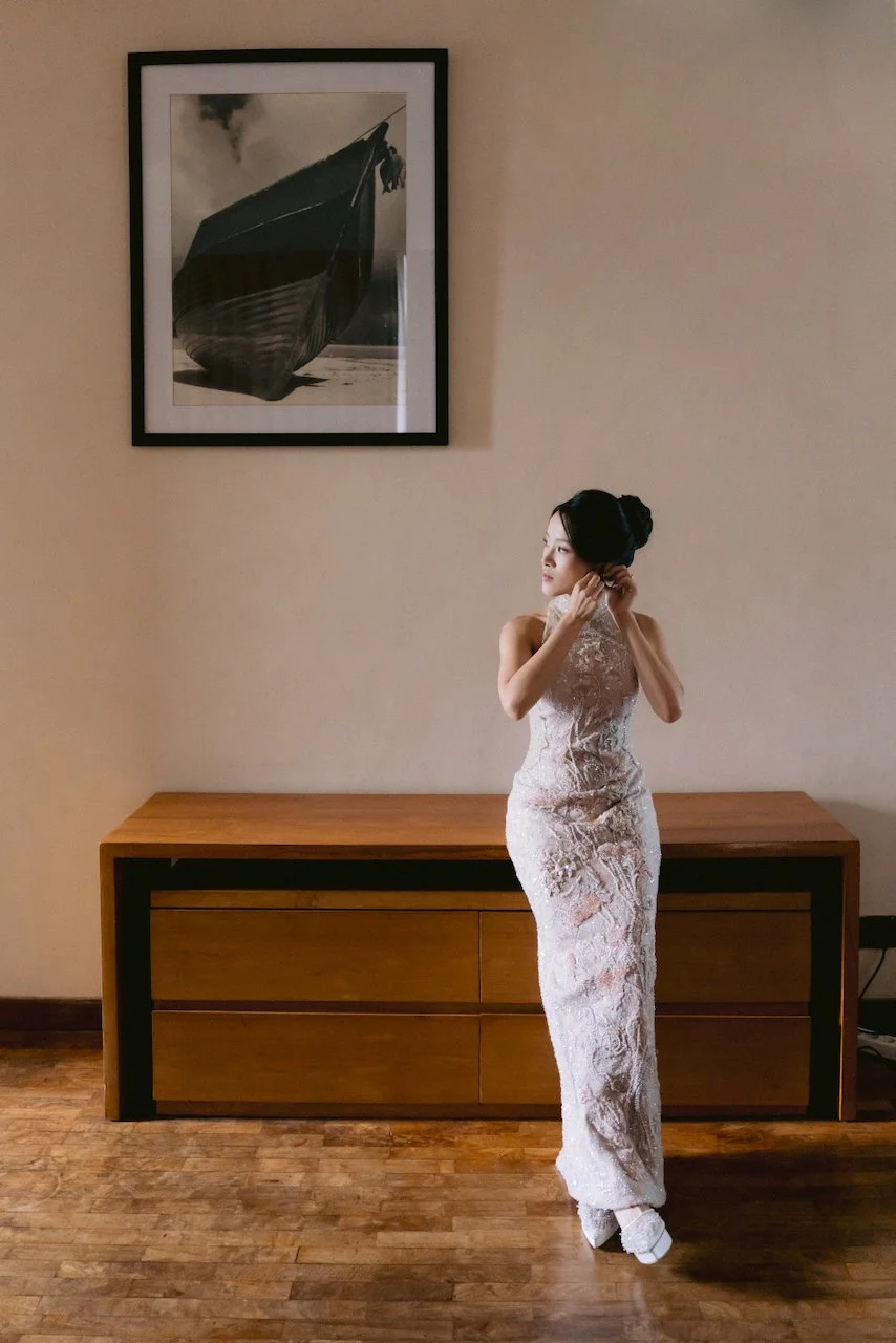 Bride Felicia wearing a white lace cheongsam standing in her getting ready suite