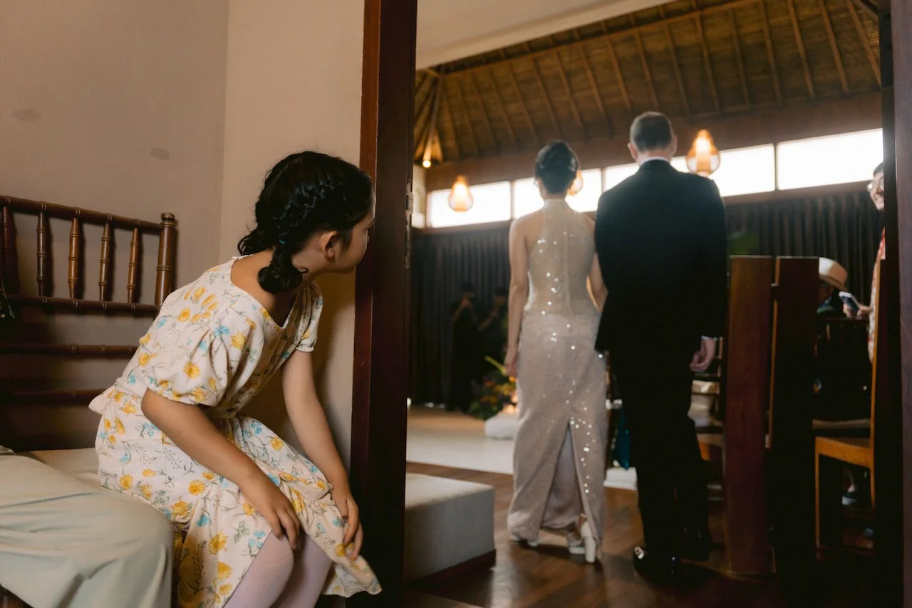 Bridesmaid watching the bride and groom walk through a dark wooden doorway
