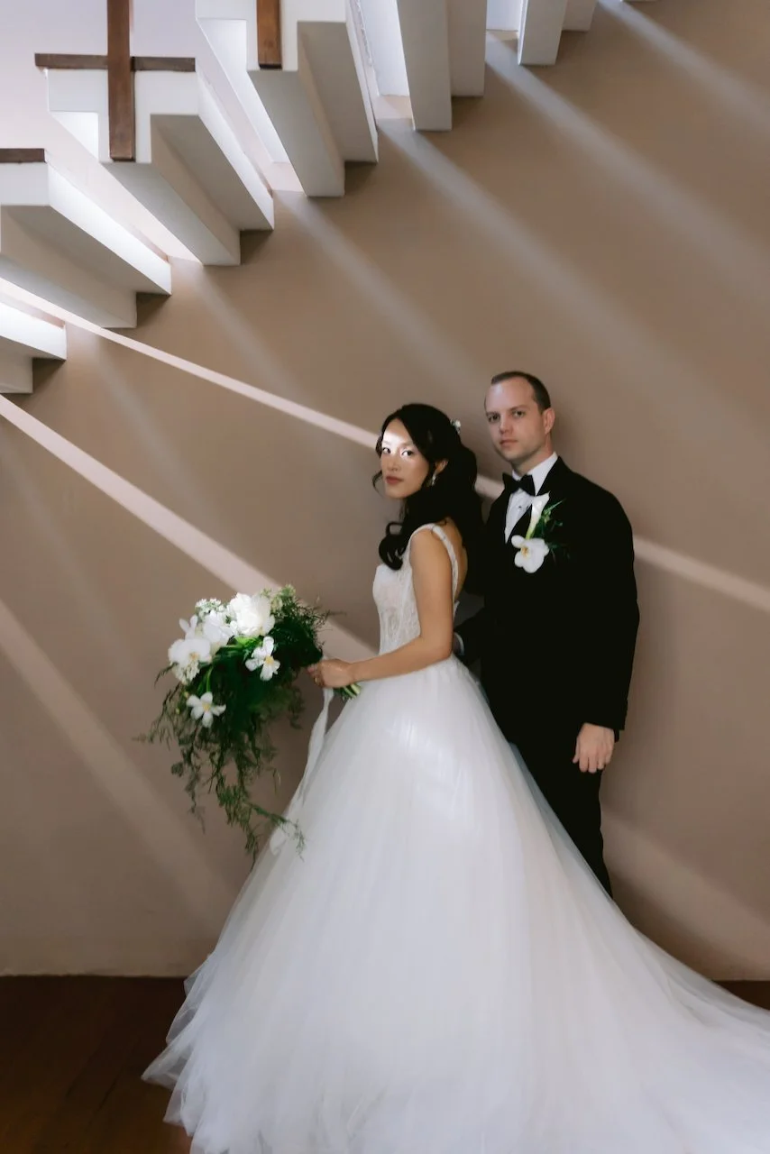 Bride and groom standing together in a modern staircase with dramatic lighting