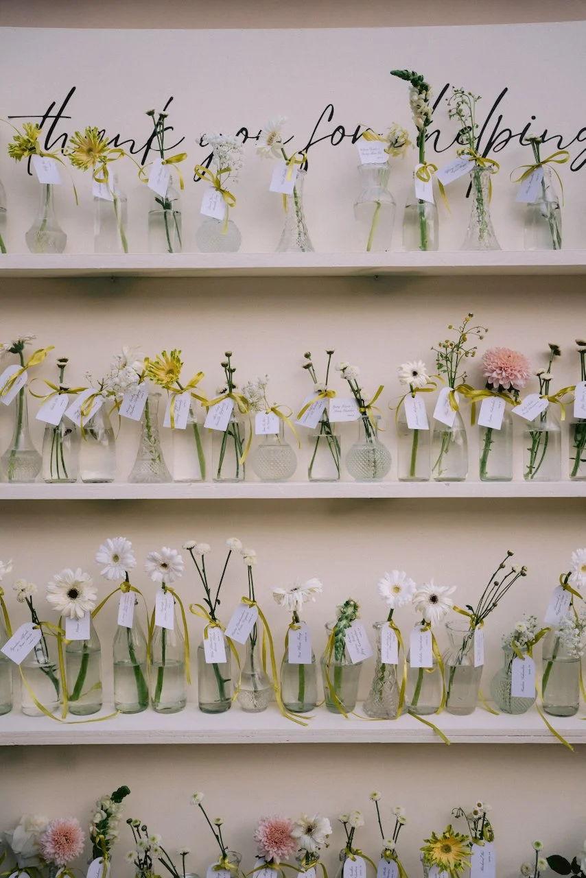 Display shelf featuring small glass vases with single flowers for wedding guests
