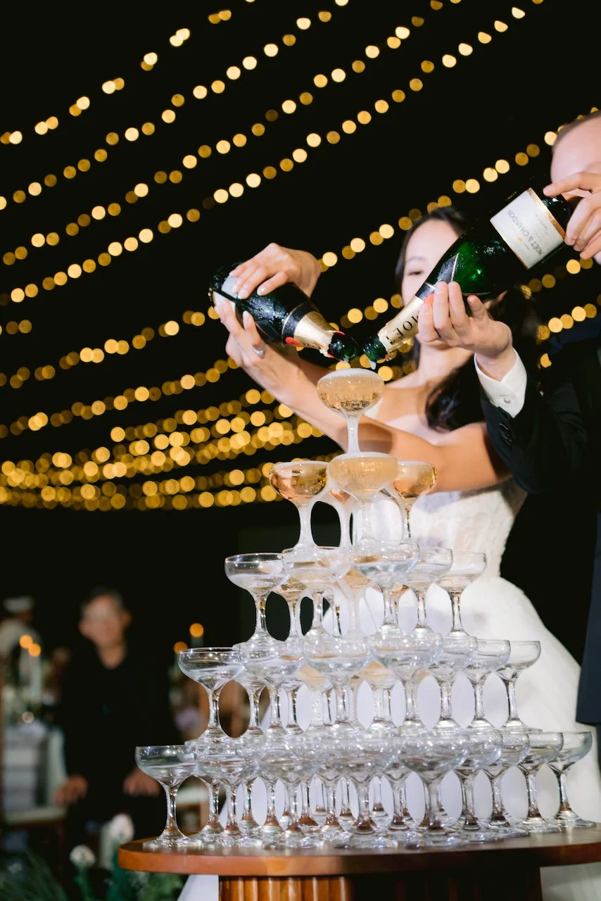 Forrest and Felicia pouring a champagne tower at their evening wedding reception