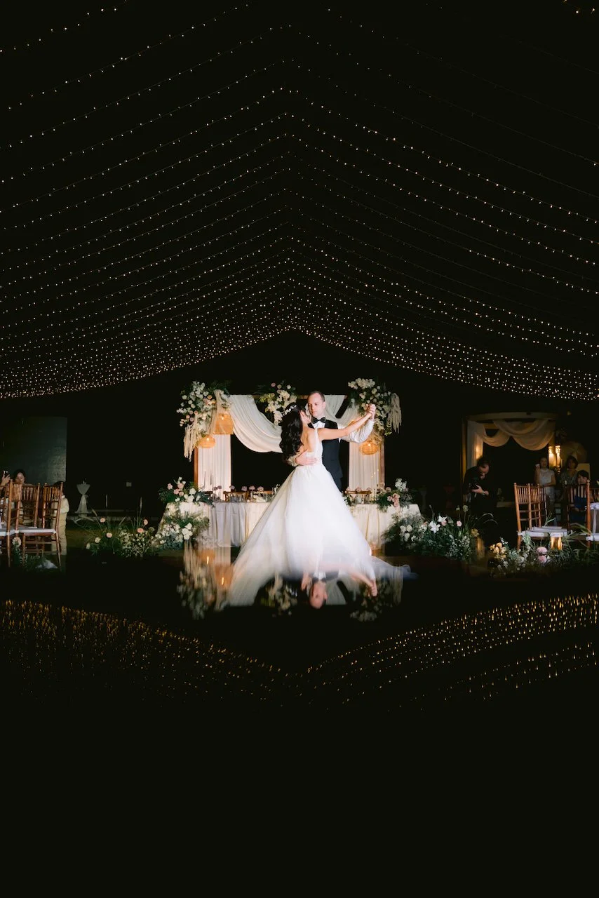 Bride and groom dancing on a wooden dance floor under fairy lights