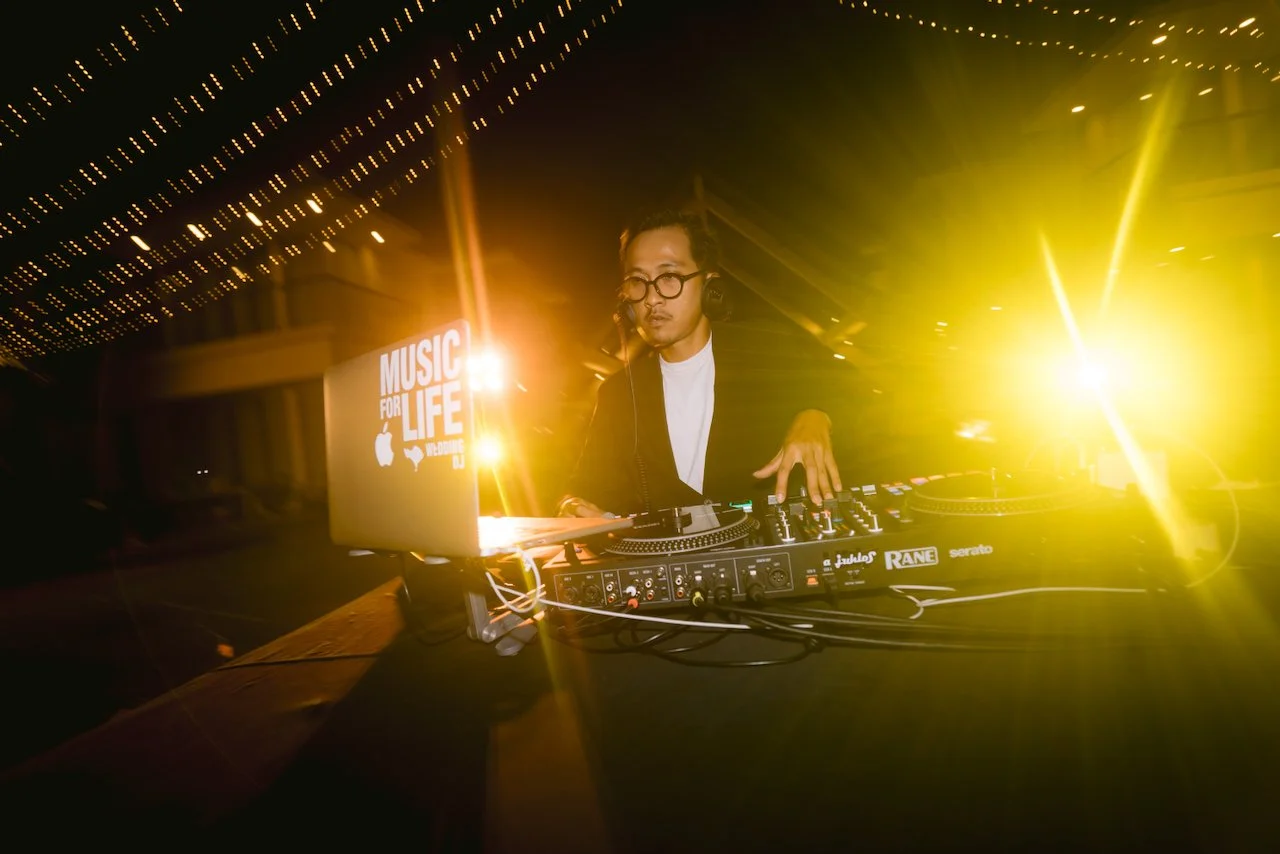 Wedding DJ mixing music on a turntable with yellow stage lighting