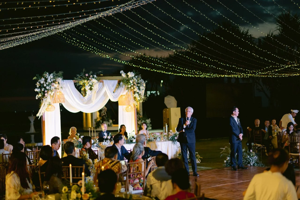 Wide view of an outdoor wedding reception with a wooden dance floor on the grass