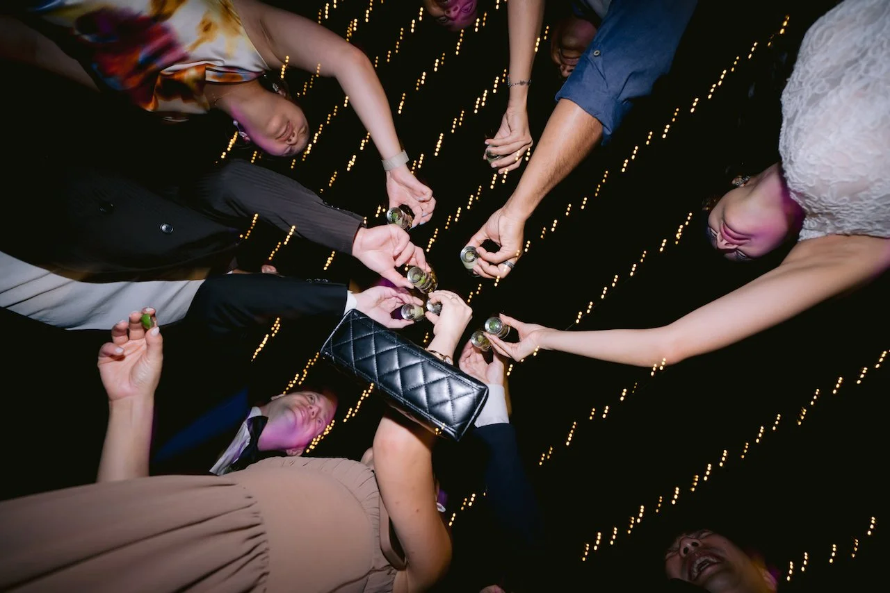 Low angle view of wedding guests doing a group cheers with shot glasses on the dance floor