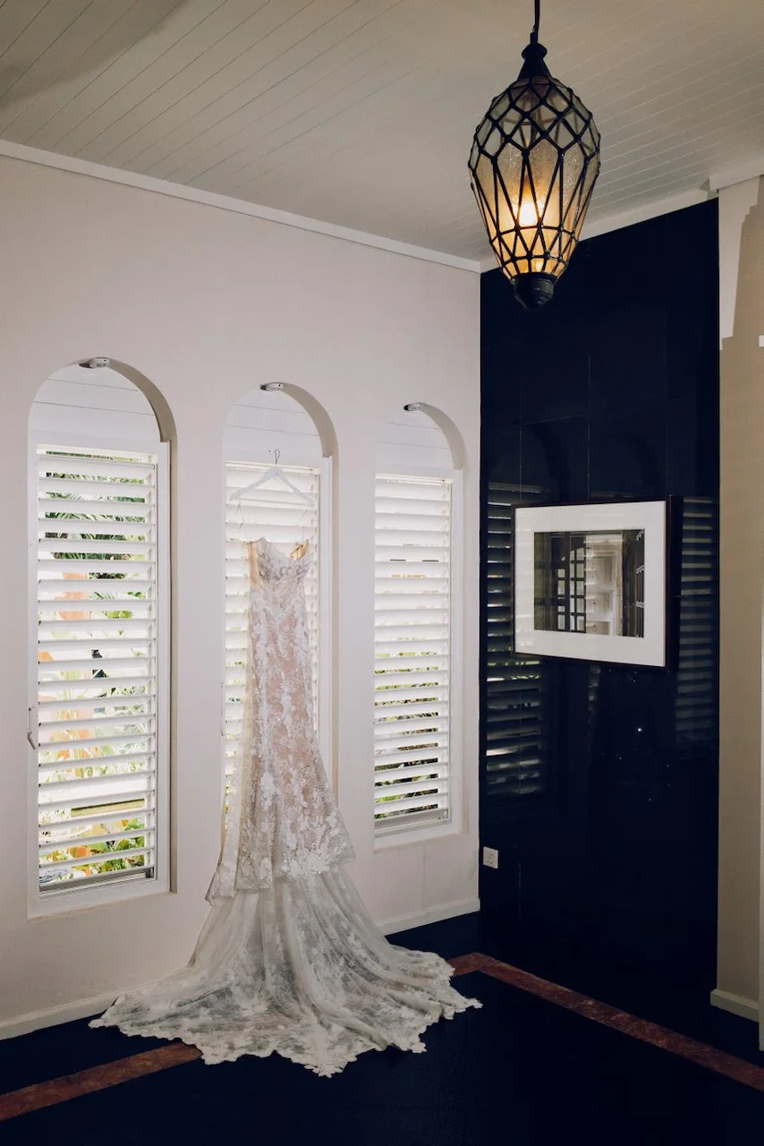 White lace wedding dress hanging in a modern villa hallway with blue walls