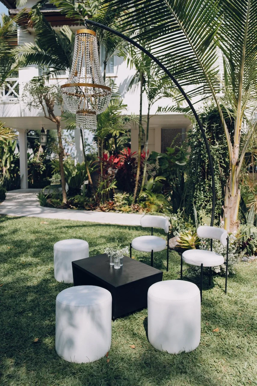 White ottomans and cocktail tables set up on a grassy lawn at Puri Nirwana