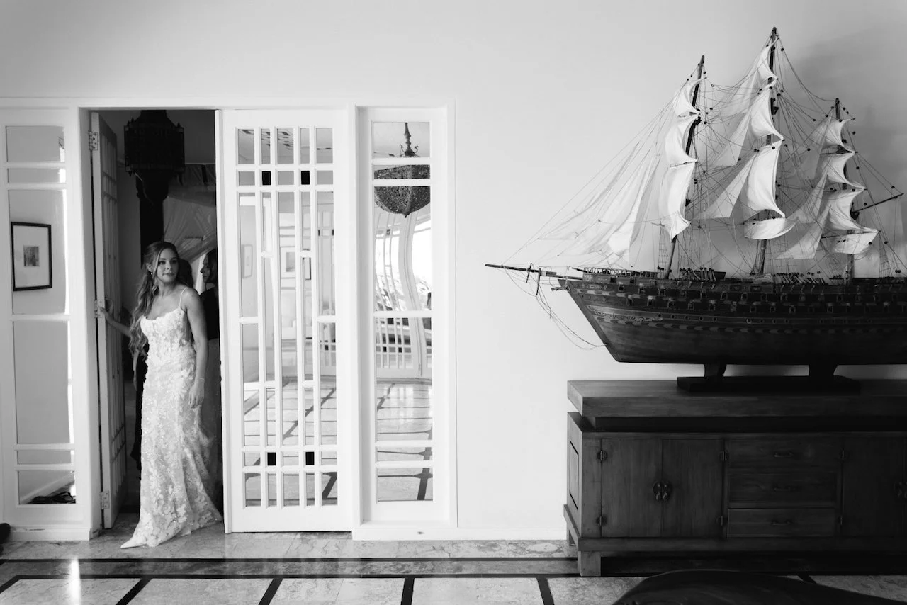 Black and white photo of bride Catherine standing in a bright villa doorway