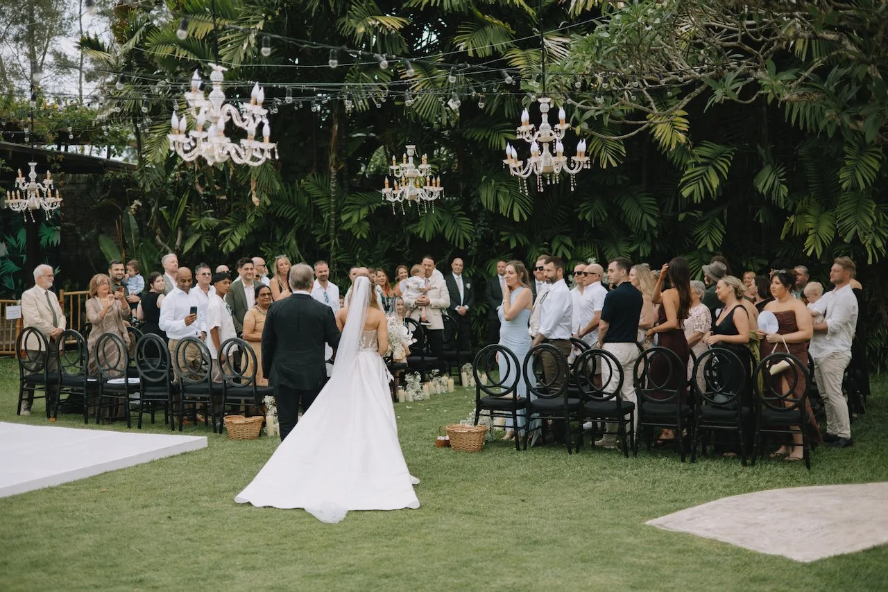 Bride Catherine walking down the grassy aisle at her outdoor villa wedding