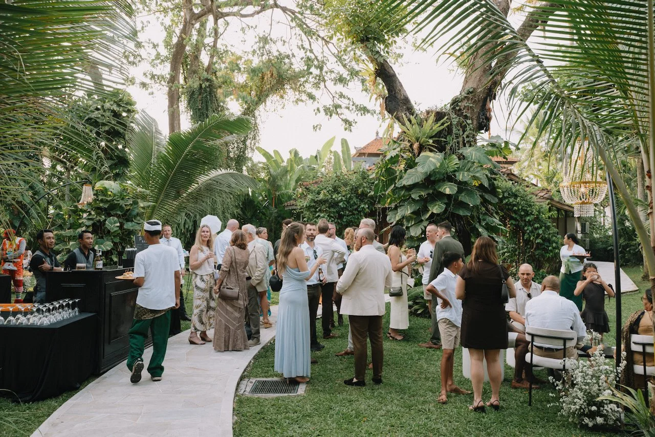 Wedding guests chatting next to an outdoor bar set up on a villa lawn