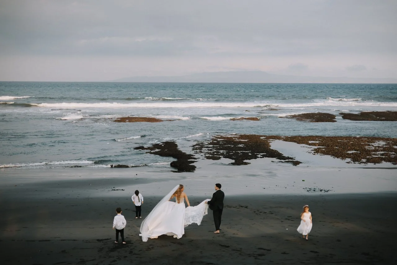 Catherine and David walking on a black sand beach for their wedding portraits