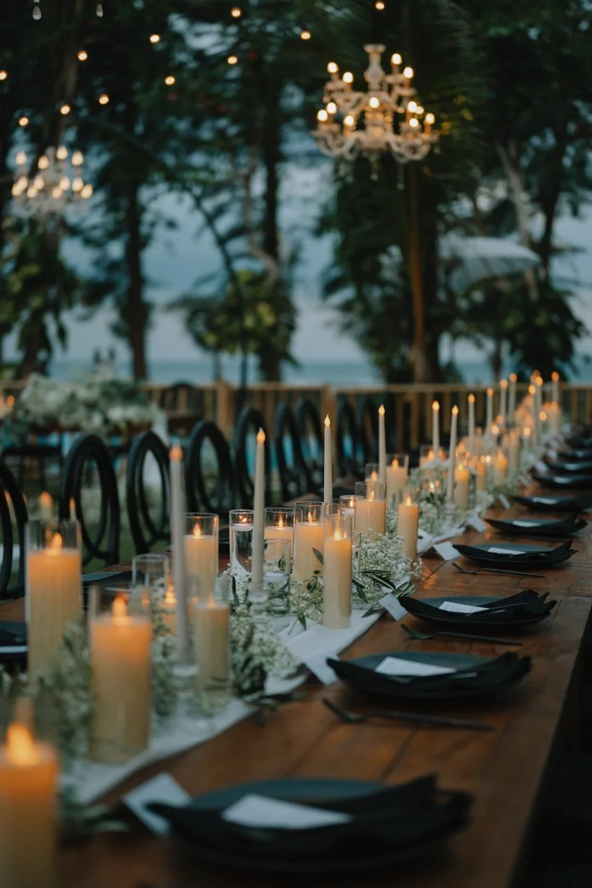 Close up of white candles and black plates on a wooden banquet table