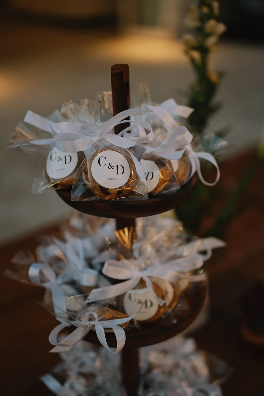 Tiered dessert stand displaying custom wedding favors wrapped in white ribbons
