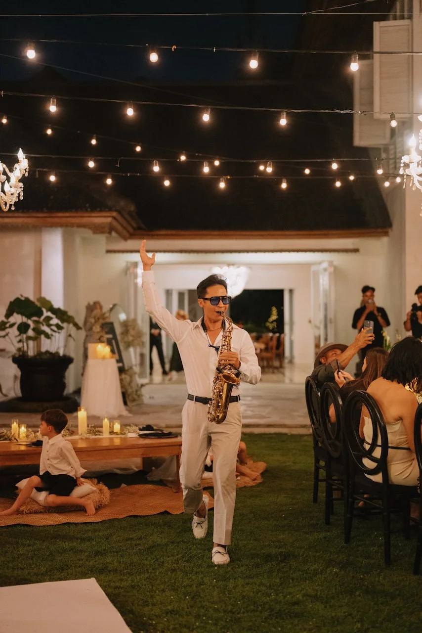 Musician playing the saxophone as guests take their seats at an outdoor reception