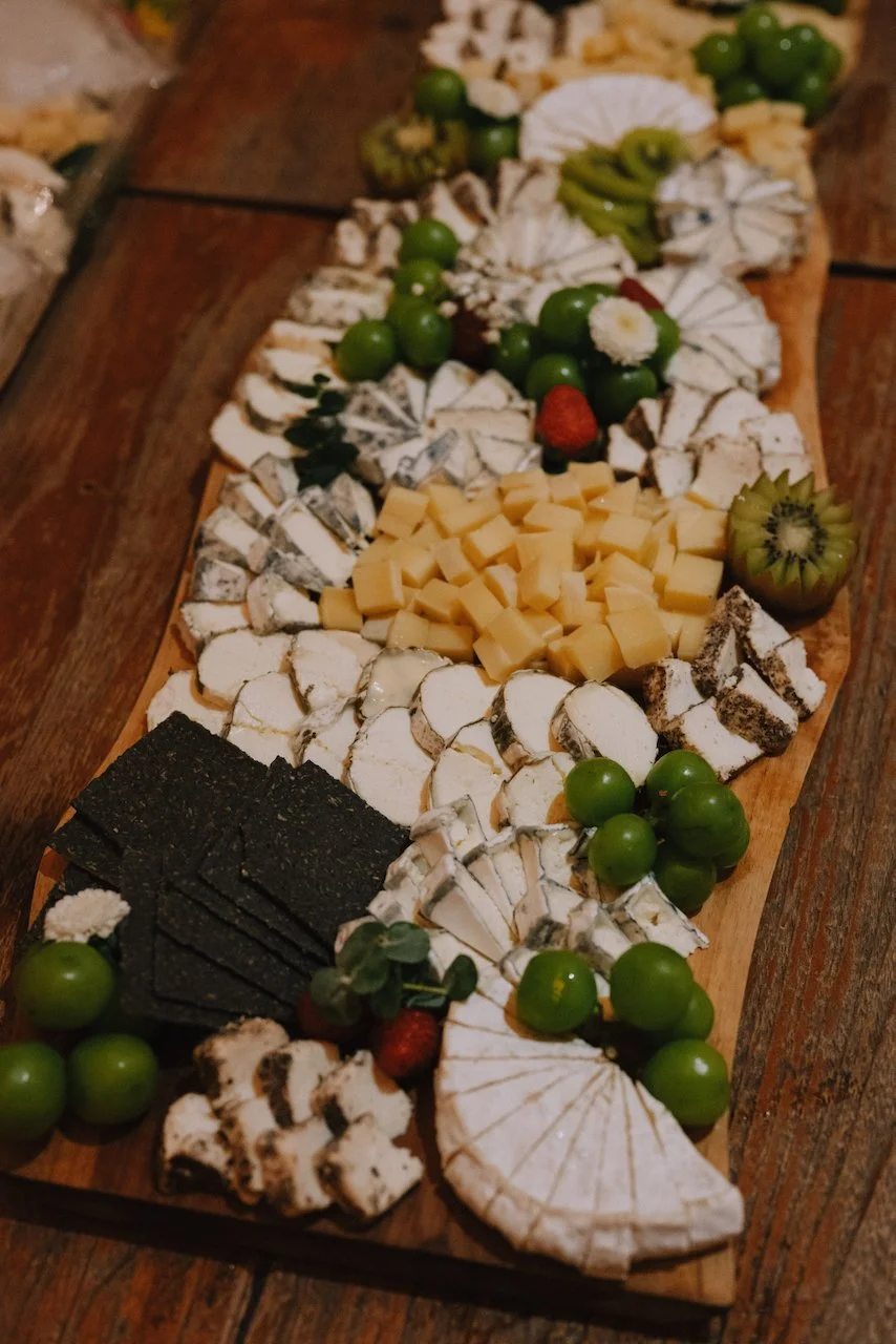 Large wooden grazing board filled with artisanal cheeses and fresh fruit