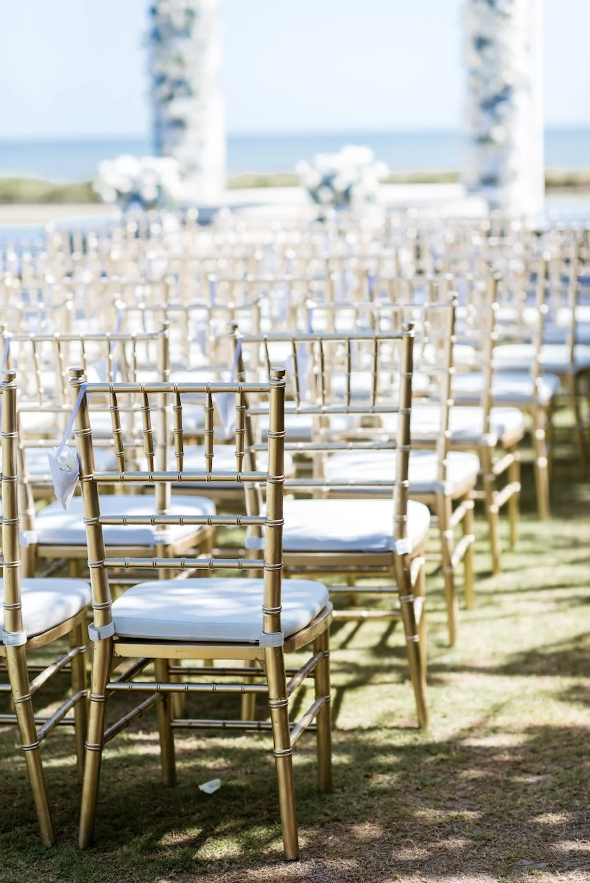 Rows of gold wedding chairs arranged for the ceremony