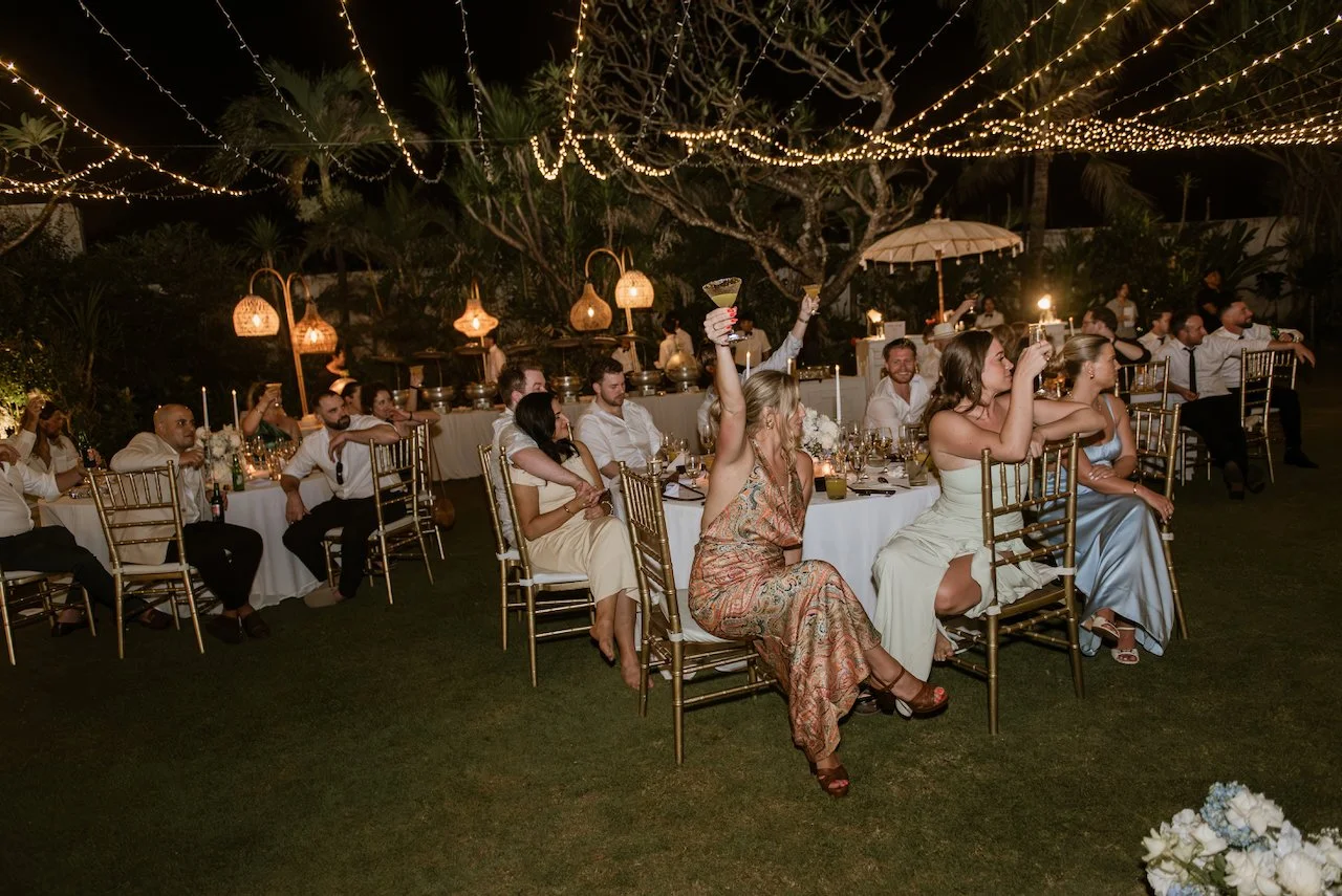Wedding guests seated outdoors beneath hanging lights