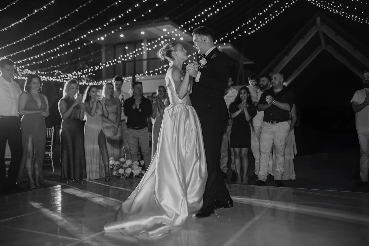 Bride and groom dancing together with guests watching