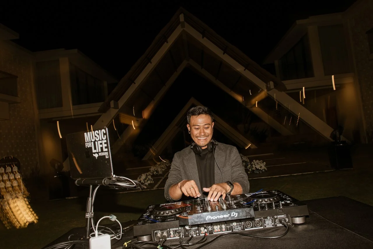 DJ performing beneath the string lights at the wedding reception
