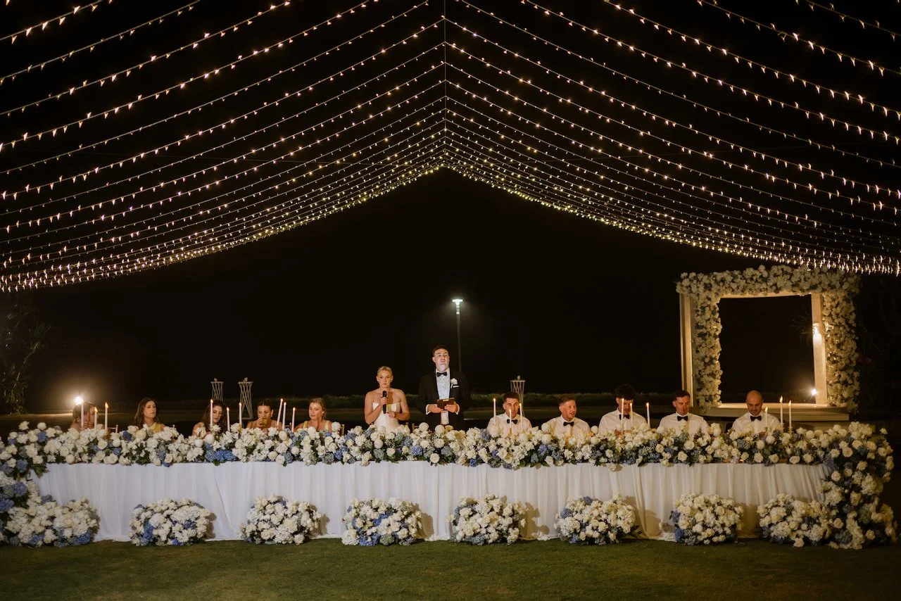 Outdoor wedding reception decorated with white flowers and string lights