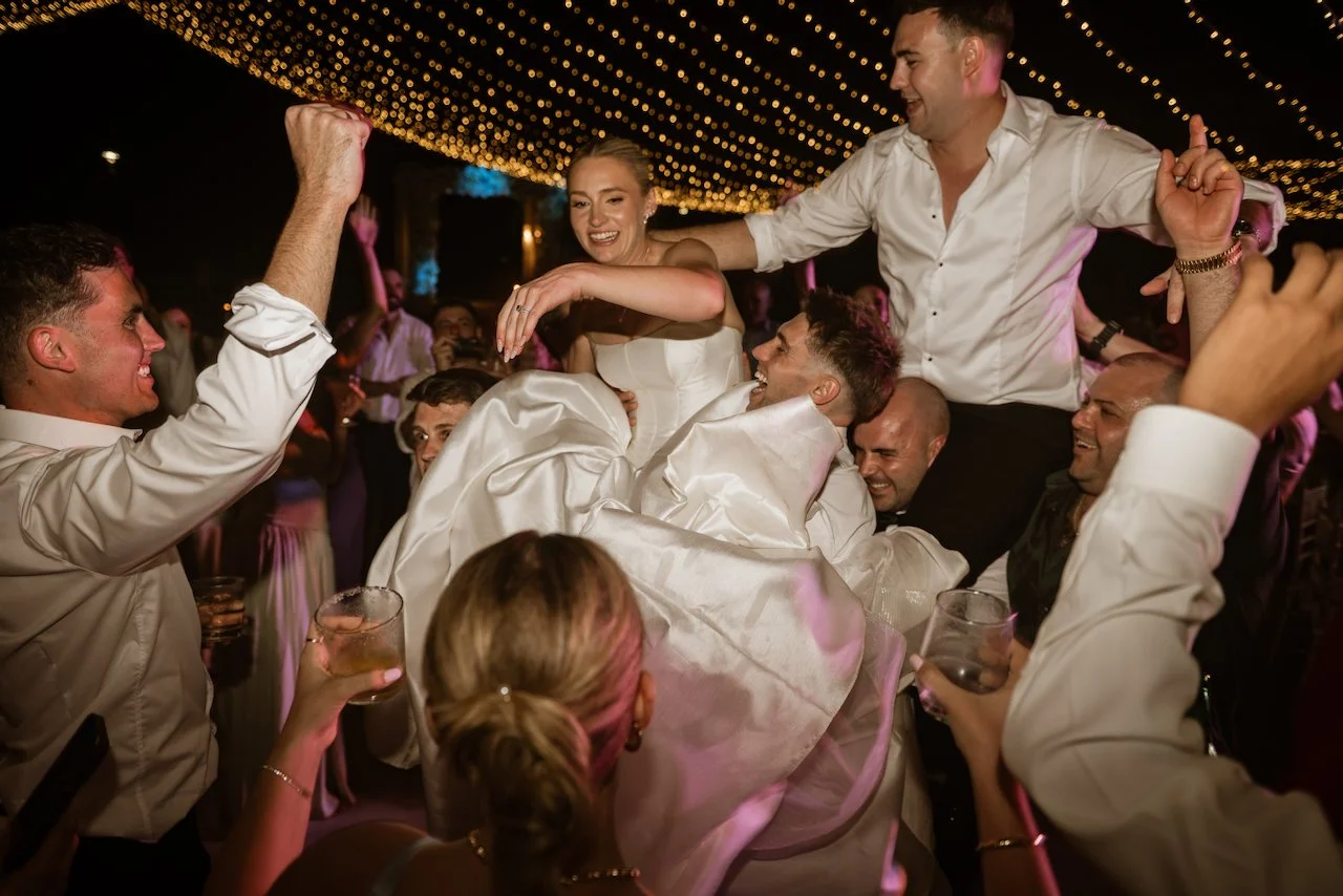 Wedding guests dancing together beneath the string lights