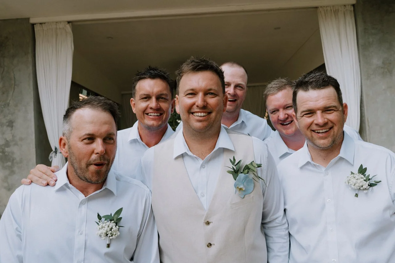 Matt laughing with his groomsmen, all wearing white shirts and floral boutonnieres