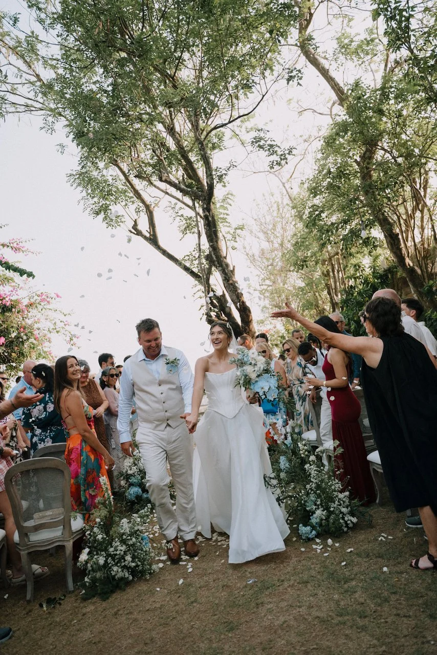Kelly and Matt walking back up the aisle as guests throw white petals