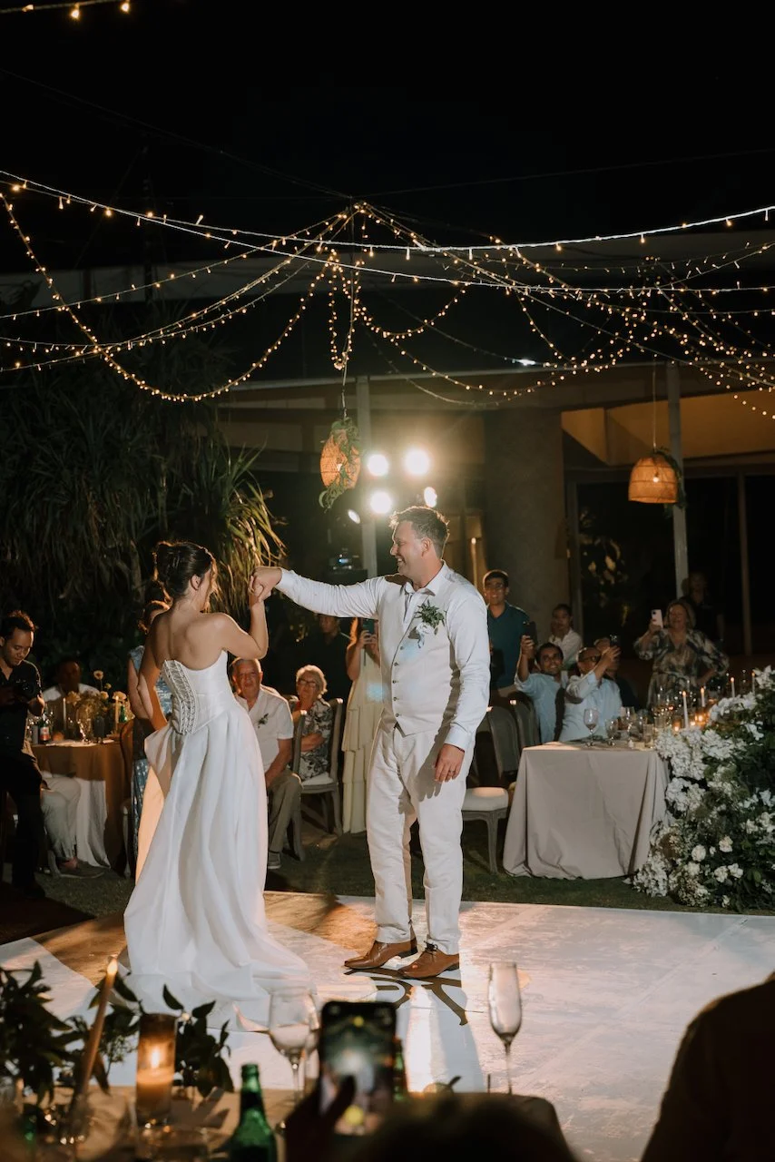 Matt twirling Kelly in their first dance on the white dance floor under fairy lights