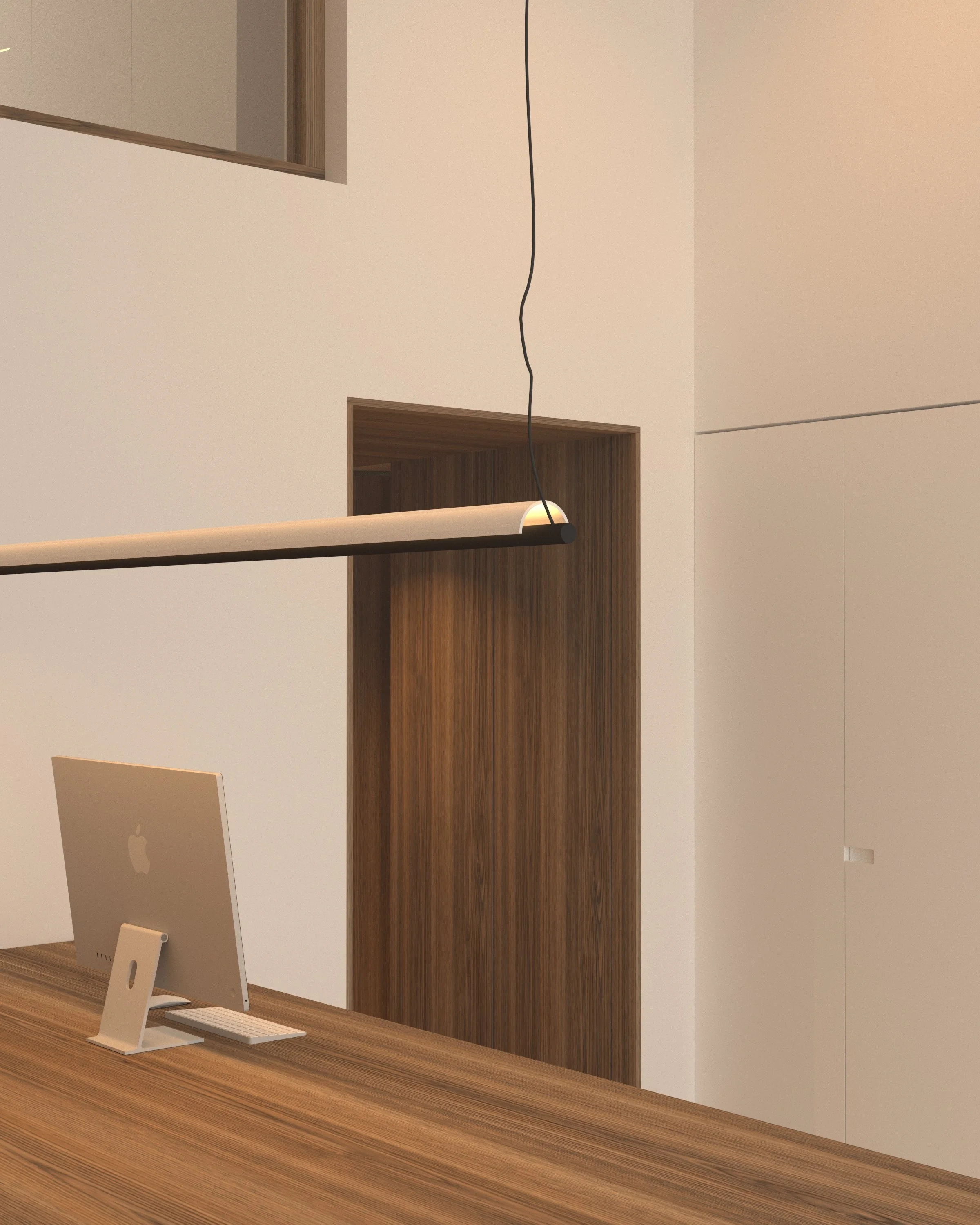 Modern office workspace with a wooden desk, an iMac computer, a sleek hanging desk lamp, and a combination of white and wood-paneled walls.