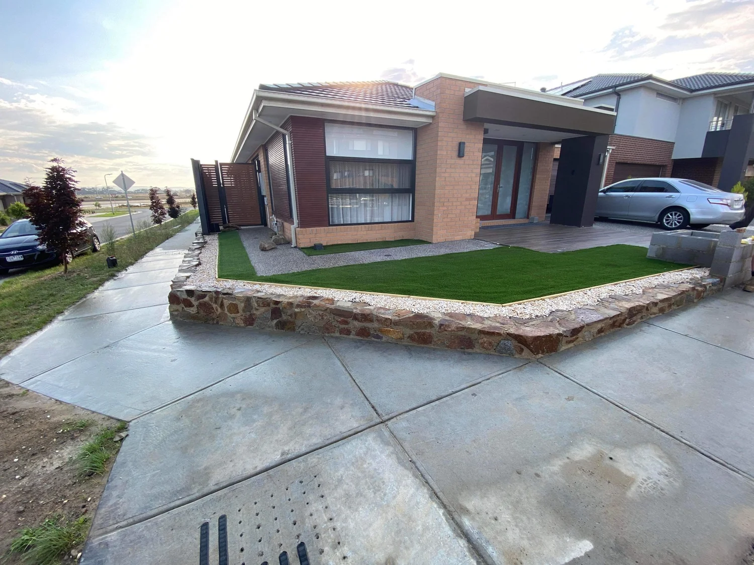 Stacked rock retaining wall with synthetic turf in a new estate front yard
