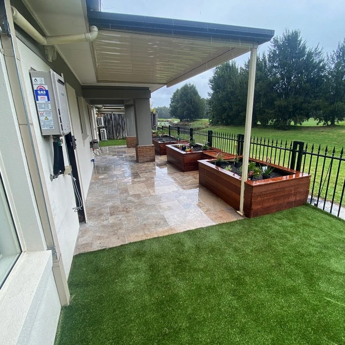 Alfresco paving, synthetic turf and timber planter boxes beside a covered patio