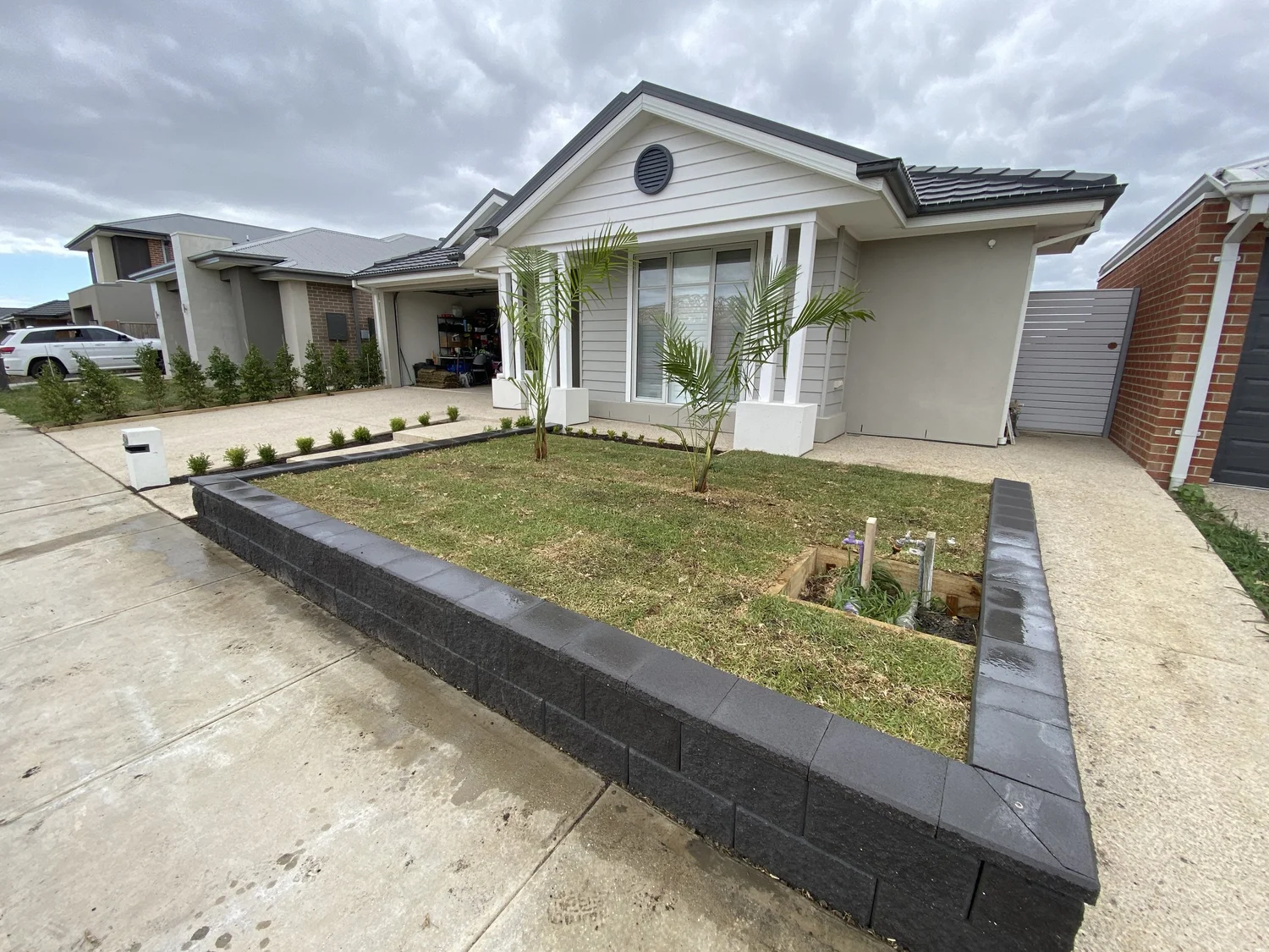 New front yard with lawn, charcoal block garden bed edging and a young tree