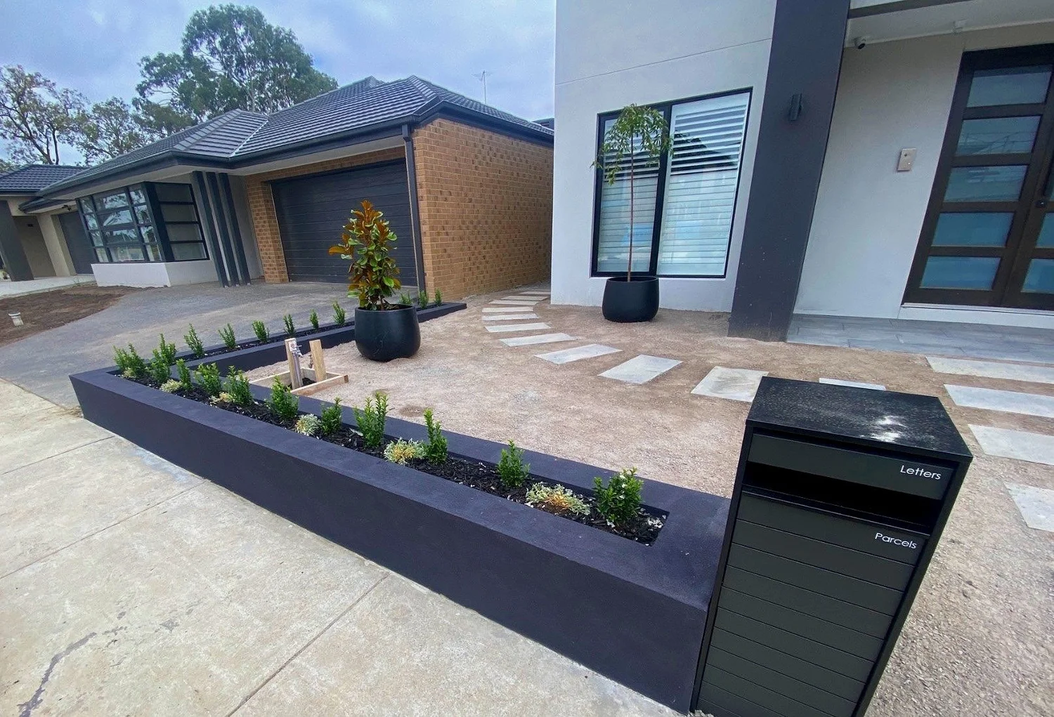 Front yard with charcoal block garden bed edging, planting and stepping-stone paving