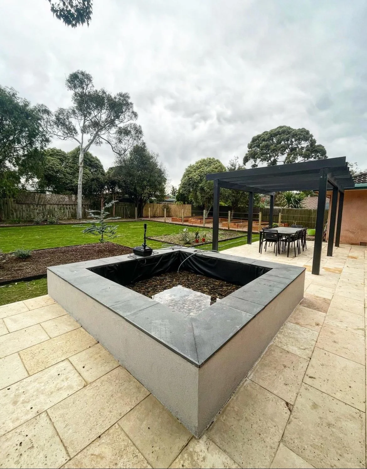 Paved courtyard with square raised planter and pergola on a new build