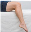 Close-up of a person's legs and feet resting on a white surface