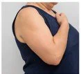 Close-up of a woman wearing a blue sleeveless top, with her arms crossed.